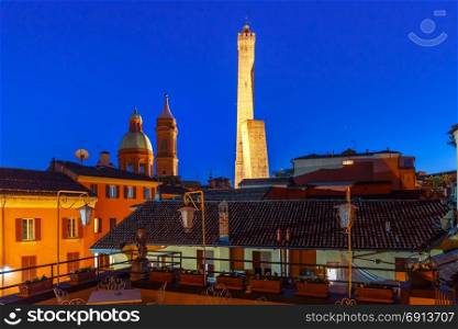 Famous Two Towers of Bologna at night, Italy. Aerial view of Two Towers, Asinelli and Garisenda, both of them leaning, symbol of Bologna and Church of Saints Bartholomew and Gaetano, during evening blue hour , Emilia-Romagna, Italy