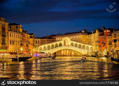 Famous Venetian tourist landmark Rialto bridge  Ponte di Rialto  over Grand Canal illuminated at night in Venice, Italy. Rialto bridge Ponte di Rialto over Grand Canal at night in Venice, Italy