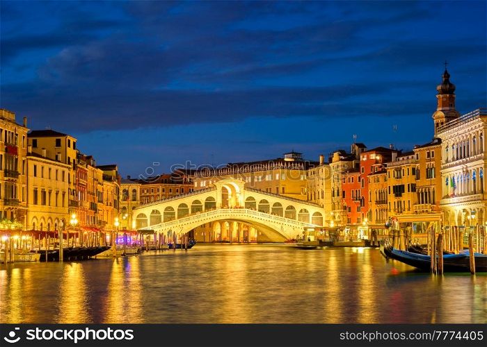 Famous Venetian tourist landmark Rialto bridge (Ponte di Rialto) over Grand Canal illuminated at night in Venice, Italy. Rialto bridge Ponte di Rialto over Grand Canal at night in Venice, Italy