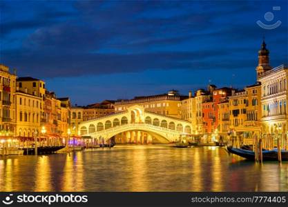 Famous Venetian tourist landmark Rialto bridge (Ponte di Rialto) over Grand Canal illuminated at night in Venice, Italy. Rialto bridge Ponte di Rialto over Grand Canal at night in Venice, Italy