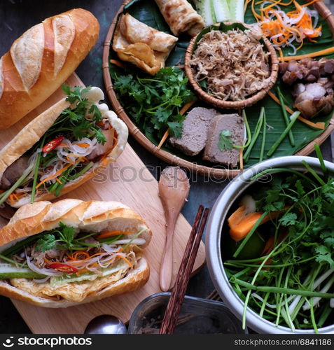 Famous Vietnamese food is banh mi thit, popular street food from bread stuffed with raw material: pork, ham, pate, egg and fresh herbs as scallions, coriander, carrot, cucumber, chilli.