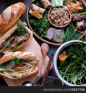 Famous Vietnamese food is banh mi thit, popular street food from bread stuffed with raw material: pork, ham, pate, egg and fresh herbs as scallions, coriander, carrot, cucumber, chilli.