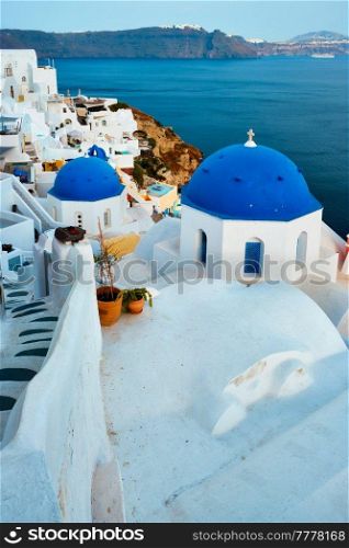 Famous view from viewpoint of Santorini Oia village with blue dome of whitewashed greek orthodox Christian church of traditional greek architecture. Oia town, Santorini island, Greece. Famous view from viewpoint of Santorini Oia village with blue dome of greek orthodox Christian church