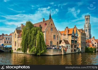 Famous view of Bruges tourist landmark attraction - Rozenhoedkaai canal with Belfry and old houses along canal with tree. Brugge, Belgium. Famous view of Bruges, Belgium