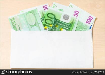 fan from several one hundred euro notes in open mail envelope on wooden table