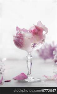Fancy drink in wide ch&agne glass with pink flowers and ice cubes