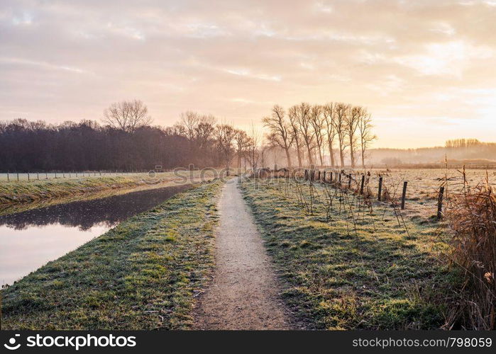 Fantastic calm river with fresh grass in the sunset. Beautiful green winter landscape on a cold day in the morning in the Netherlands beauty. Fantastic calm river with fresh grass in the sunset. Beautiful green winter landscape on a cold day in the morning in the Netherlands