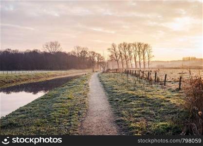 Fantastic calm river with fresh grass in the sunset. Beautiful green winter landscape on a cold day in the morning in the Netherlands beauty. Fantastic calm river with fresh grass in the sunset. Beautiful green winter landscape on a cold day in the morning in the Netherlands