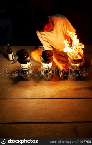Fantastic fire flames, the old man with three vintage kerosene pressure lanterns on wooden at night, beautiful brightly burning gas. The Lamplighter. Copy space. Shallow dept of field. Rural of Thailand.