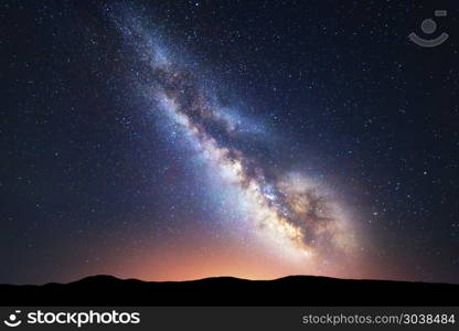 Fantastic night landscape with bright milky way. Milky Way. Fantastic night landscape with bright milky way, sky full of stars, yellow city light and mountains. Picturesque scene with our universe. Space background. Amazing astrophotography