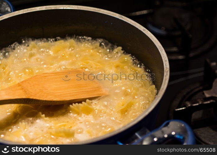 farfalle pasta boiling in saucepan dark background