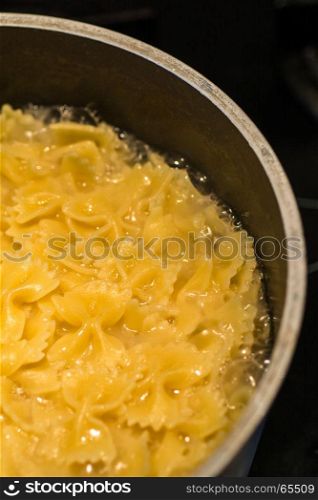 farfalle pasta boiling in saucepan dark background