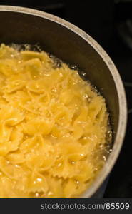 farfalle pasta boiling in saucepan dark background