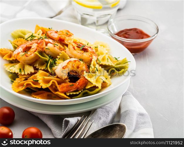 Farfalle pasta with shrimps on a light gray background