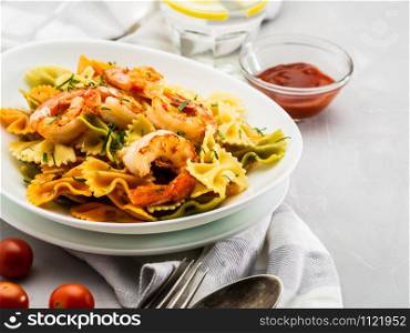 Farfalle pasta with shrimps on a light gray background