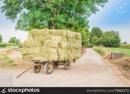 Farm cart with hay bales stacked left on the road