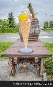 Farm cart with large plastic ice cream, and a wine barrel