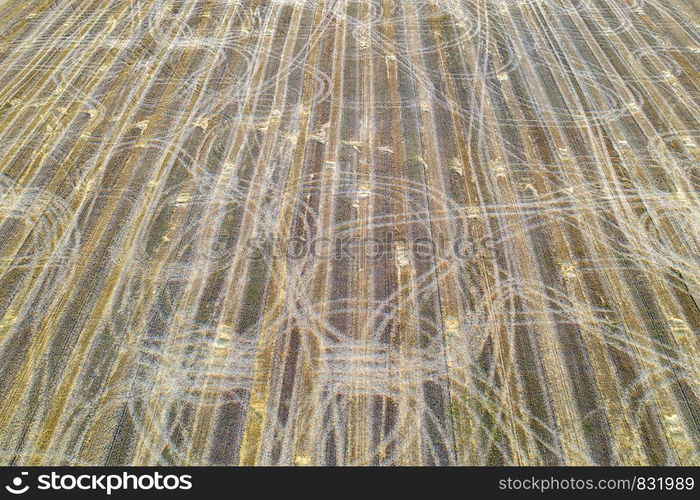 Farm field with tractor traces after harvest, views from above. Nature background.