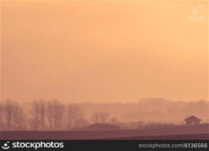 Farm house on a misty field in the sunrise