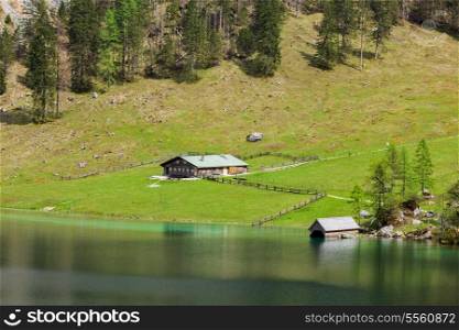 Farm house on mountain lake Obersee lake in spring. Bavaria, Germany