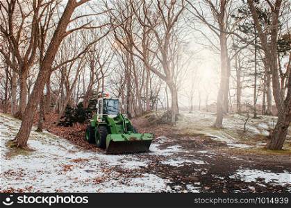 Farm Tractor under leafless tree with snow covered ground in winter. Hakodate, Hokkaido - Japan