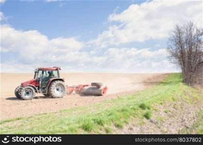 Farm work. Tractor compresses the soil after planting with rollers.