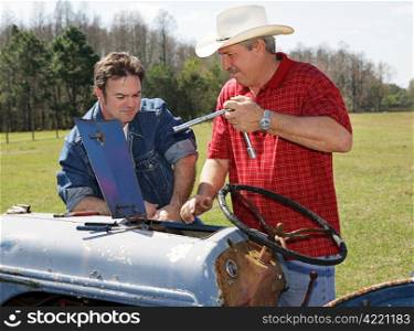 Farmer and agriculture worker repairing a tractor.