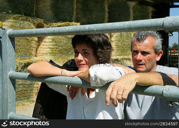 Farmer and his wife standing by metal gate