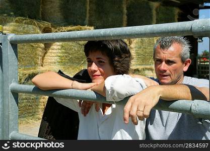 Farmer and his wife standing by metal gate