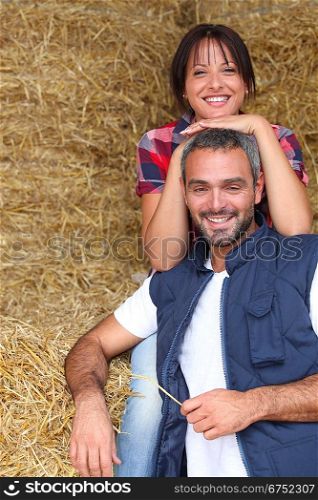 Farmer couple sitting amongst hay bales