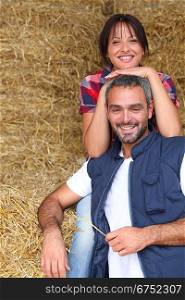 Farmer couple sitting amongst hay bales