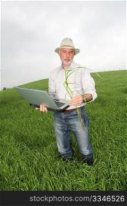 Farmer examining crop with laptop computer