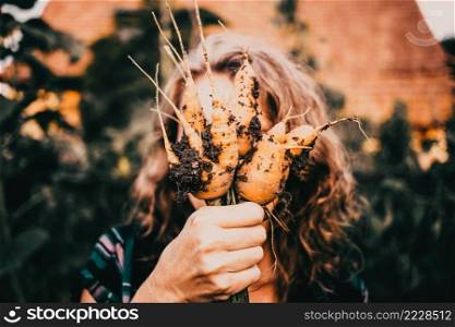 farmer holding fresh bunch of carrots in garden organic farming concept