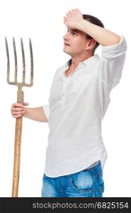 Farmer in a white shirt with a pitchfork in his hand wiping the sweat from his forehead is isolated