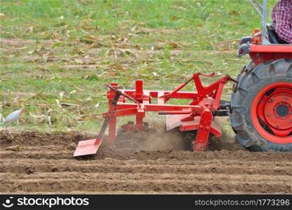 Farmer in tractor plowing land with red tractor for agriculture
