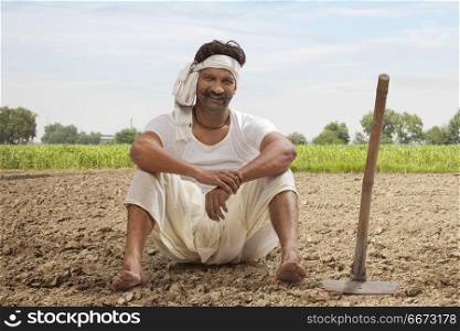 Farmer is sitting in field with hoe