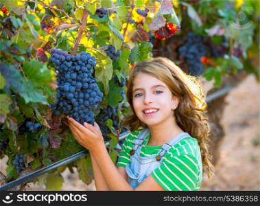 Farmer kid girl in vineyard harvest autumn leaves in mediterranean field