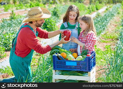 Farmer man showing vegetables harvest to kid girls in orchard