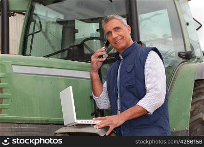 farmer near a tractor with computer