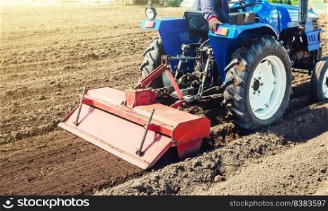 Farmer on a tractor cultivates land after harvesting. Development of agricultural technologies. Grinding loosening plowing crumbling soil for further sowing by cultivated plants. Milling machine