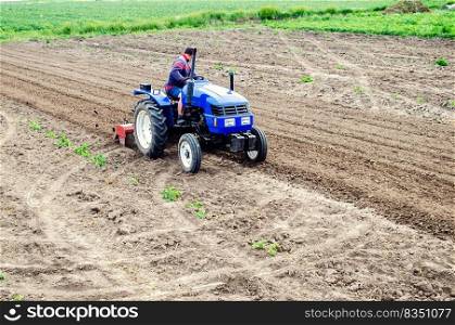 Farmer on a tractor loosens soil with milling machine. First stage of preparing soil for planting. Loosening surface, land cultivation. Use agricultural machinery. Farming, agriculture. Plowing field.. Farmer on a tractor loosens soil with milling machine. Plowing field. First stage of preparing soil for planting. Loosening surface, land cultivation. Use agricultural machinery. Farming, agriculture.