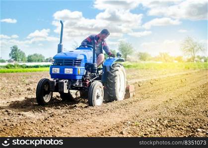 Farmer on a tractor loosens the soil with milling equipment. Loosening surface, land cultivation Use of agricultural machinery and to simplify and speed up work. Farming, agriculture. Plowing field.