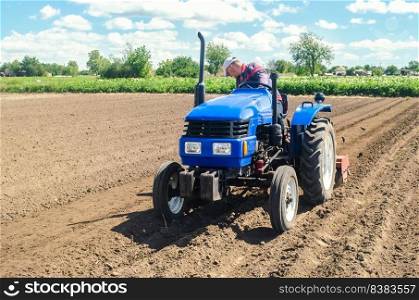 Farmer on a tractor loosens the soil with milling equipment. Loosening surface, land cultivation. Farming, agriculture. Plowing field. Use of agricultural machinery and to simplify and speed up work.