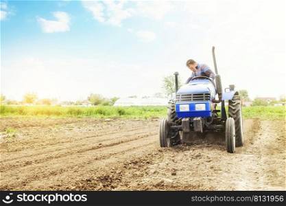 Farmer on a tractor with milling machine loosens, grinds and mixes soil. Loosening surface, cultivating the land for further planting. Farming and agriculture. Use of agricultural machinery on a farm.