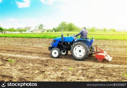 Farmer on a tractor with milling machine loosens, grinds and mixes soil. Field preparation for new crop planting. Work on preparing the soil for a sowing of seeds of agricultural crops.