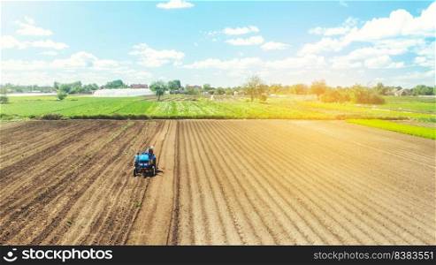 Farmer on tractor loosens and grinds the soil. Preparing the land for a new crop planting. Farming and agriculture. agricultural sector of the economy. Loosening the surface, cultivating the land.