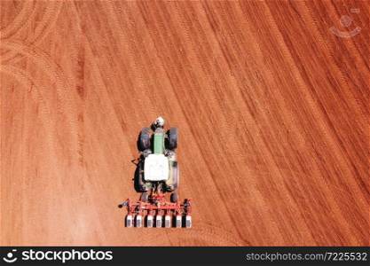 Farmer seeding, sowing crops at field with tractor.Sowing is the process of planting seeds in the ground as part of agricultural activities .. Farmer seeding, sowing crops at field with tractor. Sowing is the process of planting seeds in the ground as part of agricultural activities.