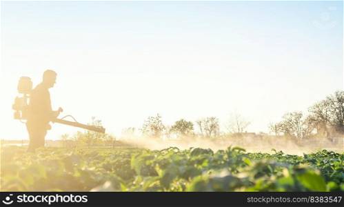 Farmer spraying plants with pesticides in the early morning. Protecting against insect and fungal infections. The use of chemicals in agriculture. Agriculture and agribusiness, agricultural industry.