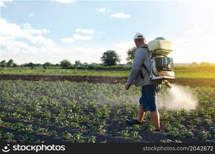 Farmer sprays a potato plantation with a sprayer. Chemical treatment. Mist sprayer, fungicide and pesticide. Effective crop protection of cultivated plants against insects and fungal. Working on field