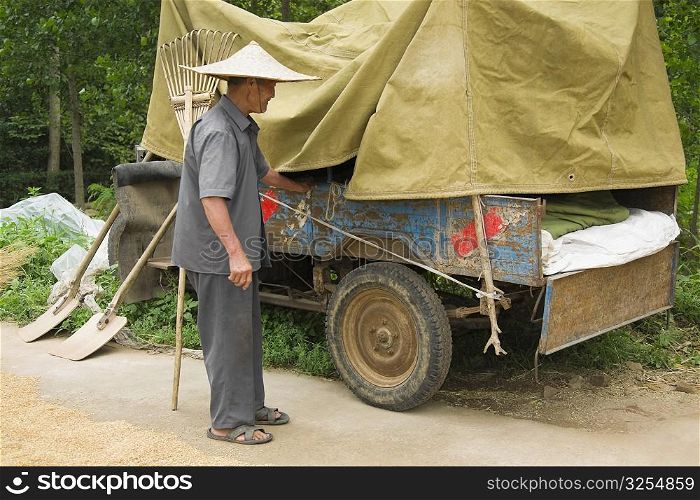 Farmer standing beside a vehicle trailer, Zhigou, Shandong Province, China